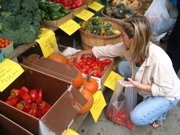 Customer shopping for tomatoes at a farmers' market.